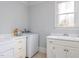 Functional laundry room with white cabinets, utility sink, and a washing machine and dryer at 3359 Hampton Rd, Raleigh, NC 27607