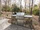 Outdoor kitchen with a stone grill, stainless steel features, and a brick paved patio in a backyard setting at 3359 Hampton Rd, Raleigh, NC 27607