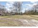 Large backyard featuring a partial fence, sparse grass, and mature trees at 628 East Ave, Henderson, NC 27536