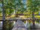 A wooden dock leads to a backyard with lake access, surrounded by mature trees and lush greenery, making it a serene retreat at 93 Shoreline Dr, Princeton, NC 27569