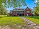 Expansive backyard view of a brick home with a screened porch, stone pathway, and lush lawn leading to the house at 93 Shoreline Dr, Princeton, NC 27569