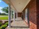 Spacious covered porch with brick flooring, elegant columns, and lush greenery, perfect for outdoor living at 93 Shoreline Dr, Princeton, NC 27569