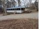 Single-story home features a long screened porch and covered parking, with a gravel driveway and woodsy surroundings at 122 Tomahawk Dr, Louisburg, NC 27549