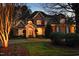 Stunning two-story home featuring stone and brick facade, manicured lawn, and welcoming front porch with a double-door entryway at 12417 Richmond Run Dr, Raleigh, NC 27614