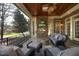 Covered patio has a stone fireplace, TV, and outdoor seating with wooded views at 12417 Richmond Run Dr, Raleigh, NC 27614