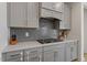 Modern kitchen featuring gray cabinets, stainless steel appliances, and a stylish backsplash at 133 Alumroot Road Rd, Holly Springs, NC 27540