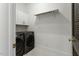 Neat laundry room with modern washer and dryer units, white cabinets, and tiled floor at 1354 Briar Chapel Pkwy, Chapel Hill, NC 27516
