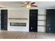 Bright living room features a sleek fireplace with wooden mantle, custom built-ins, light hardwood floors and ceiling fan at 2112 Hamrick Dr, Raleigh, NC 27615