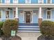 Inviting front porch with a decorated wooden door, porch lighting, and manicured landscaping at 2118 Cloud Cover Ln, Raleigh, NC 27614