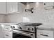 Close up of a professional grade stove with marble backsplash and white cabinetry at 2218 Woodrow St, Durham, NC 27705