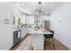 Stylish white kitchen features stainless steel appliances, modern light fixture, island with chairs, and hardwood floors at 2218 Woodrow St, Durham, NC 27705