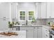 Bright kitchen showcasing white cabinets, marble counters, stainless steel appliances, and a view of lush backyard at 2218 Woodrow St, Durham, NC 27705