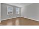 An empty bedroom with hardwood floors and two windows that provide natural light at 2220 Stillness Pond Ln, Apex, NC 27539