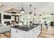 Open-concept kitchen with a black marble island, white cabinets, and a view into the adjacent living room at 2404 Del Webb Gardens Dr, Fuquay Varina, NC 27526
