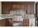 Well-equipped outdoor kitchen with stainless steel grill, rich wood cabinets, and tiled backsplash at 266 Perfect Moment Dr, Durham, NC 27713