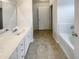 Bathroom with white cabinetry, a single vanity, neutral-toned tile flooring, and a bathtub with tile surround at 4 Birkdale Ct, Durham, NC 27713