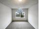 A well-lit bedroom featuring a large window with a view of the outdoors and neutral-toned carpet at 4 Birkdale Ct, Durham, NC 27713