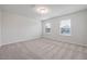 Bright, empty bedroom with neutral carpet, two windows, and white walls, ready for personalization at 505 Providence Springs Ln, Fuquay Varina, NC 27526