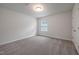 Neutral carpeted bedroom with a window and a door, offering a blank canvas for new homeowners at 505 Providence Springs Ln, Fuquay Varina, NC 27526