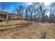Lush backyard with mature trees, a covered patio, and space for outdoor activities at 513 W Glendale St, Siler City, NC 27344