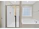 Bathroom with glass door shower and soaking tub, enhanced by natural light from a frosted window at 622 Lone Pine Loop, Fuquay Varina, NC 27526