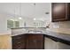Close-up of kitchen sink with granite countertop, dark cabinets, and view to adjacent living spaces at 622 Lone Pine Loop, Fuquay Varina, NC 27526
