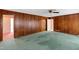 Spacious living room featuring wood-paneled walls, carpet, and an open doorway at 817 Glen Eden Dr, Raleigh, NC 27612