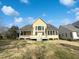 Charming yellow home boasts a well-manicured lawn and a covered porch, blending comfort and curb appeal at 9100 Palm Bay Cir, Raleigh, NC 27617