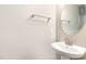 Modern powder room with a pedestal sink, round mirror, and neutral color palette at 121 Mason Oaks Dr, Wake Forest, NC 27587