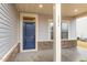 Inviting covered front porch featuring a navy blue front door, stone accents, and well-maintained columns at 121 Mason Oaks Dr, Wake Forest, NC 27587