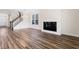 Bright living room with dark hardwood floors, fireplace, staircase, and modern lighting with large windows at 1785 Birdhaven Ln, Wendell, NC 27591