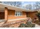 Close up exterior of brick home, highlighting the covered porch with brick accents and meticulously trimmed shrubs at 1837 Shamrock Dr, Burlington, NC 27215