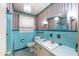 Charming blue tiled bathroom with a vintage vanity, wallpaper, and decorative light fixtures at 2608 Walley St, Rocky Mount, NC 27803