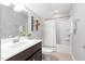 Bright bathroom featuring a shower-tub combo, vanity with sink and dark wood cabinetry, and neutral-toned tile flooring at 3924 Overcup Oak Ln, Cary, NC 27519