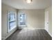 A carpeted room with windows and neutral walls, providing a versatile space at 4 Strowd Ct, Durham, NC 27703