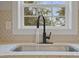Close up of a kitchen sink with granite countertops, black faucet, and backyard view at 408 Charlotte Ave, Sanford, NC 27330