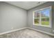 Bedroom with neutral carpet and paint, white trim and one window letting in light at 507 W Edwards St, Princeton, NC 27569