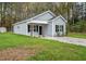 A cozy single-story home with gray siding and a well-maintained lawn surrounded by lush trees at 507 W Edwards St, Princeton, NC 27569