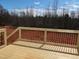 New wooden deck with metal railing overlooking the expansive backyard with wooded views and bright blue sky at 5372 Salem Woods Dr # 18, Graham, NC 27253