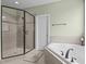 Neutral tiled bathroom features both a frameless shower and a separate tub for a relaxing and spa-like experience at 6205 Roles Saddle Dr, Rolesville, NC 27571