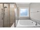Modern bathroom featuring a shower and a soaking tub under a window for a relaxing spa-like experience at 85 Willow Bend Dr, Youngsville, NC 27596
