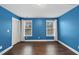 Bright bedroom with hardwood floors, two windows, and blue accent walls at 85 Willow Bend Dr, Youngsville, NC 27596