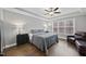 Bedroom with hardwood floors, tray ceiling, ceiling fan, and a cozy seating area next to the window at 85 Willow Bend Dr, Youngsville, NC 27596