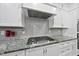 Close up of a gas range and granite countertop in a modern kitchen with white cabinets and stainless steel appliances at 85 Willow Bend Dr, Youngsville, NC 27596