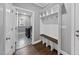 Mudroom has built-in bench with storage hooks, connecting the laundry room with patterned tile flooring at 85 Willow Bend Dr, Youngsville, NC 27596