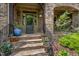 Inviting front entrance features a stone facade, a stylish front door, and decorative plants, creating a welcoming ambiance at 101 Tussled Ivy Way, Cary, NC 27513