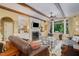 Comfortable living room with wooden beams, a fireplace, custom shelving, and large windows overlooking the backyard at 101 Tussled Ivy Way, Cary, NC 27513