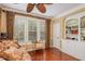 A cozy living room with a decorative ceiling fan, large windows, and built-in bookshelves at 101 Tussled Ivy Way, Cary, NC 27513