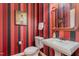 Striking powder room with red and black striped wallpaper and classic pedestal sink at 101 Tussled Ivy Way, Cary, NC 27513