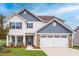 Charming two-story home with white siding, stone accents, and an attached two-car garage at 102 Wilderness Ct, Mebane, NC 27302